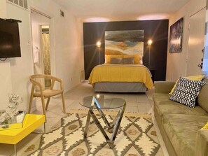 A bedroom with a bed, a sofa, a glass coffee table, and a chair. - Stay in Style! Heart of Dallas 106 (Dallas)