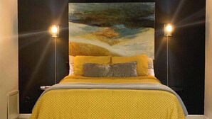 A bed with a yellow bedspread and two pillows, flanked by two wall-mounted lamps. - Stay in Style! Heart of Dallas 106 (Dallas)