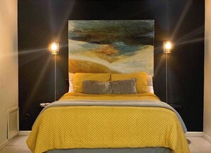 A bed with a yellow bedspread and two pillows, flanked by two wall-mounted lamps. - Stay in Style! Heart of Dallas 106 (Dallas)