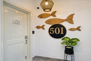 A door with the number 501, a wall with wooden fish decorations, a round sign with the number 501, and a potted plant. - Lovely 2-Bedroom Beach Apartment with Pool #2 (Punta Cana)