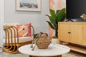 A living room with a wicker sofa, a round coffee table, a television, a cabinet, and a large plant. - Palm Paradise *Minutes to Beach* (SANTA RSA BCH)