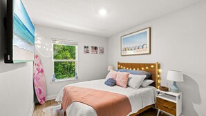 Un dormitorio con cama, mesitas de noche, ventana con vistas y decoración en la pared.