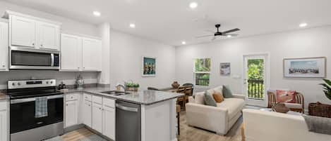 A modern kitchen with white cabinetry, a built-in oven, and a microwave.