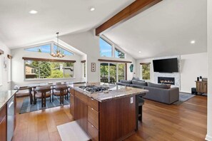 A spacious living area with a fireplace, a large TV, and a kitchen with a central island.
