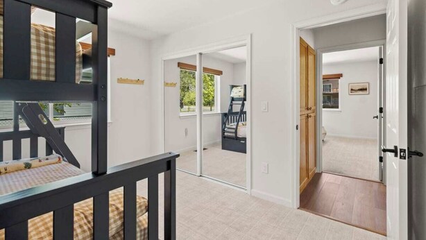 Una habitación con una cama, una ventana y una puerta que da a otra habitación.