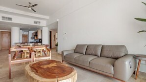 Un'ampia zona giorno con divano, tavolino in legno e ventilatore a soffitto.