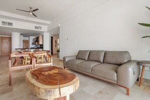 Ein geräumiger Wohnbereich mit einer Couch, einem Holztisch und einem Deckenventilator.