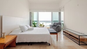 Una camera da letto moderna con un letto, una sedia, una scrivania e un'ampia finestra vista oceano.