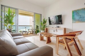 Ein modernes Wohnzimmer mit einer Couch, einem Holztisch und einem an der Wand montierten Fernseher.