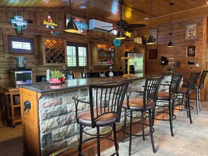 Eine rustikale Bar mit Holzwänden, Steinverzierungen und mehreren Barhocker.