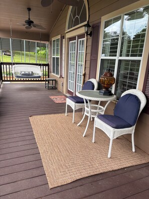 Eine überdachte Veranda mit Schaukelstuhl, Tisch und Stühlen sowie einer Zierteille.
