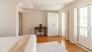 A bedroom with a bed, a desk, a chair, and a wardrobe. - Sunny Príncipe Real Villa · Patio · 4BR for 12 (Lisboa)