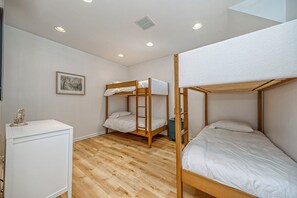 Una habitación con tres literas, un aparador blanco y un cuadro en la pared.