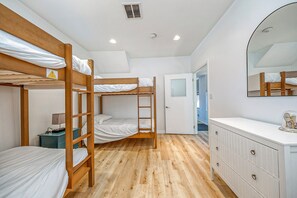 Un dormitorio con literas, una cómoda y un espejo.
