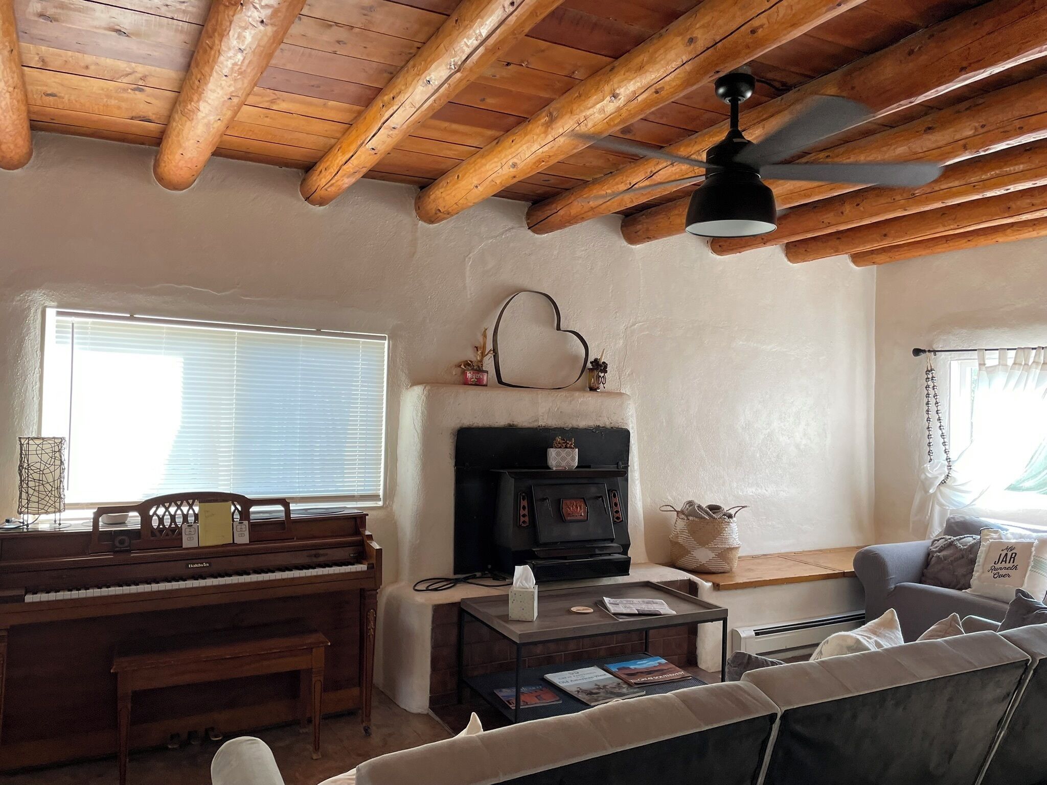 Una sala de estar acogedora con un piano, chimenea y ventilador de techo.
