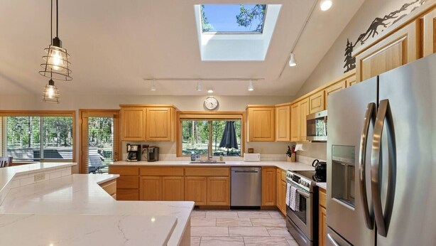 Una cocina moderna con tragaluz, electrodomésticos de acero inoxidable, armarios de madera y una isla grande.