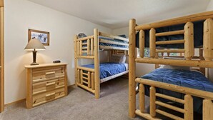Una habitación con literas, un aparador de madera y una lámpara.