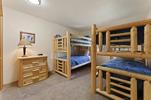 Ein Zimmer mit Etagenbetten, einem Holzschrank und einer Lampe.