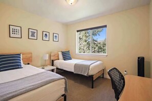 A hotel room with two beds, a window with a view, a desk, and a chair.