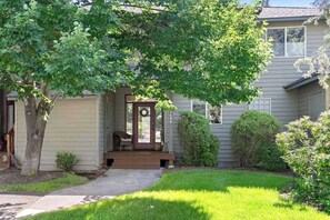 Ein Wohnhaus mit Veranda, einem Baum und einem gepflegten Rasen.