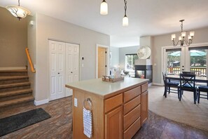 A spacious kitchen with a central island, a dining area with a table and chairs, and a staircase with a handrail.