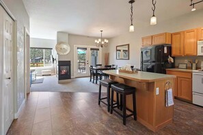 A spacious kitchen with a central island, wooden cabinets, and a built-in fireplace. - Present Pheasant - Cute & Updated, Close to Everything, Golf, Amenities, Perfect For Family (Redmond)