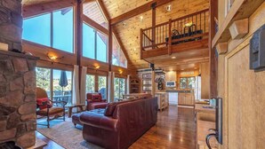 A spacious living area with a stone fireplace, a leather sofa, and a dining area with a view. - Straight From The Heart (Lyle)