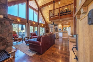 A spacious living area with a stone fireplace, a leather sofa, and a dining area with a view. - Straight From The Heart (Lyle)