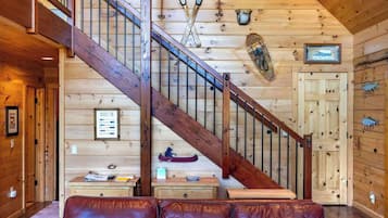 A wooden interior with a staircase, a paddleboard, and a canoe on the wall.