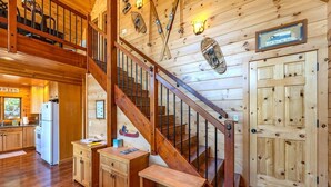 A wooden interior with a staircase, wooden cabinets, a refrigerator, and a door with a sign. - Straight From The Heart (Lyle)