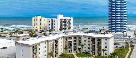 A hotel with a pool, beachfront view, and a tall building nearby.