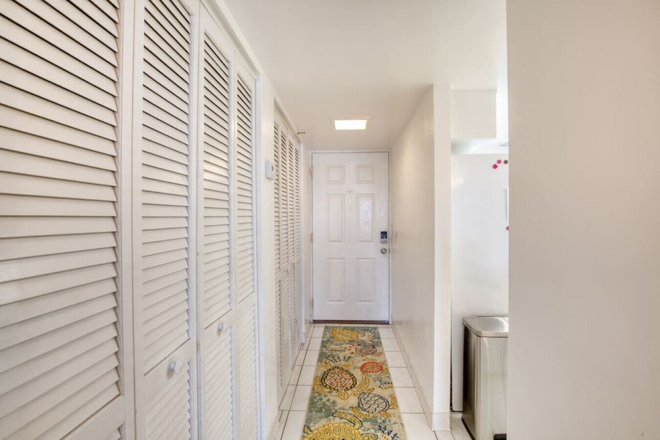 A narrow hallway with a patterned rug, white doors, and a white radiator.