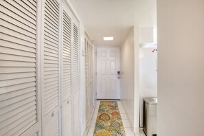 Un couloir étroit avec un tapis à motifs, des portes blanches et un radiateur blanc.