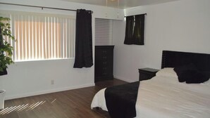 Un dormitorio con cama, mesita de noche, cómoda y ventana con persianas.