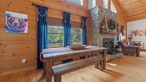A wooden interior with a stone fireplace, a bench, and a table with a placemat. - Beautiful and comfy mountain view home with outdoor living showcased! (Waynesville)