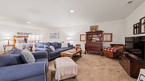 A living room with a sofa, coffee table, and a wooden cabinet. - Beautiful and comfy mountain view home with outdoor living showcased! (Waynesville)