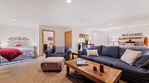 A modern living room with a sofa, a coffee table, and a bed with a headboard. - Beautiful and comfy mountain view home with outdoor living showcased! (Waynesville)