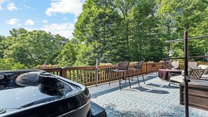 A covered outdoor area with a barbecue grill, seating, and a wooden deck. - Beautiful and comfy mountain view home with outdoor living showcased! (Waynesville)