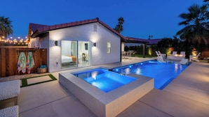 A modern house with a swimming pool, outdoor seating, and a wooden fence with a towel hanging. - Zuri Eight - Modern 3BR Oasis w Pool (Indio)
