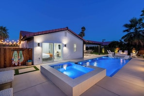 A modern house with a swimming pool, outdoor seating, and a wooden fence with a towel hanging. - Zuri Eight - Modern 3BR Oasis w Pool (Indio)