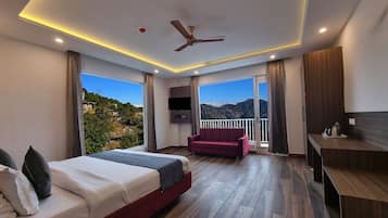 Habitación de hotel moderna con una cama grande, un sofá, un escritorio y un balcón con vista a la montaña.