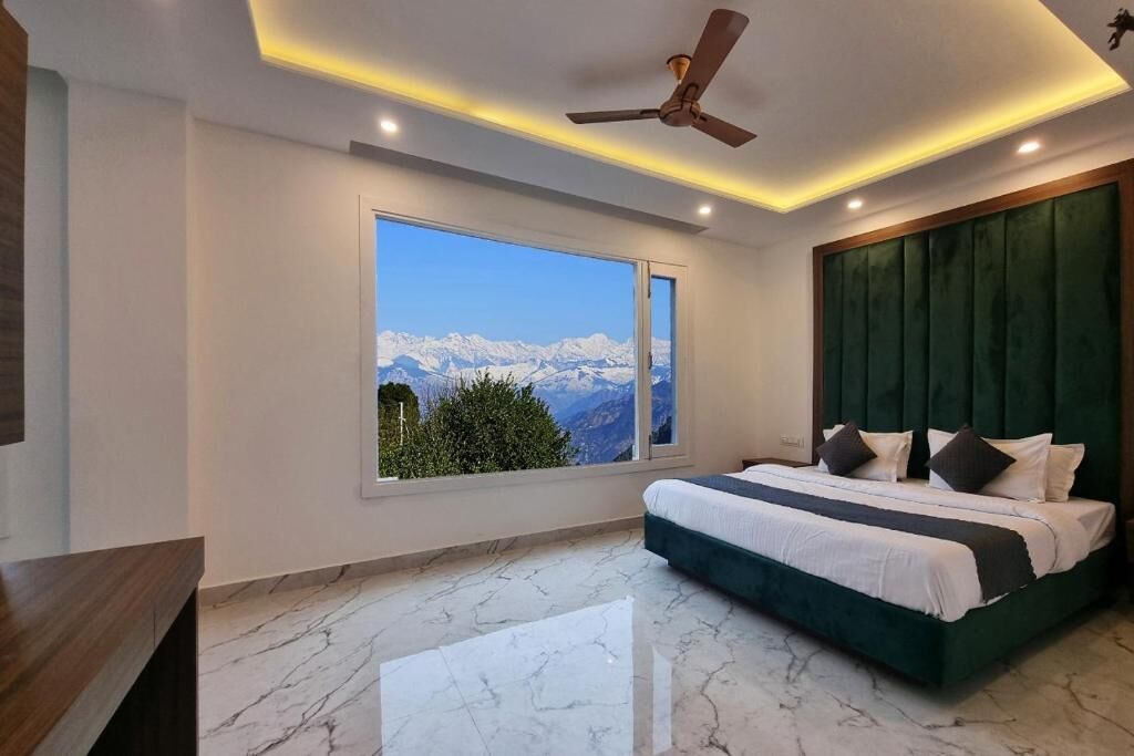 Un dormitorio con un ventanal grande, una cama, un ventilador de techo y vistas a montañas.