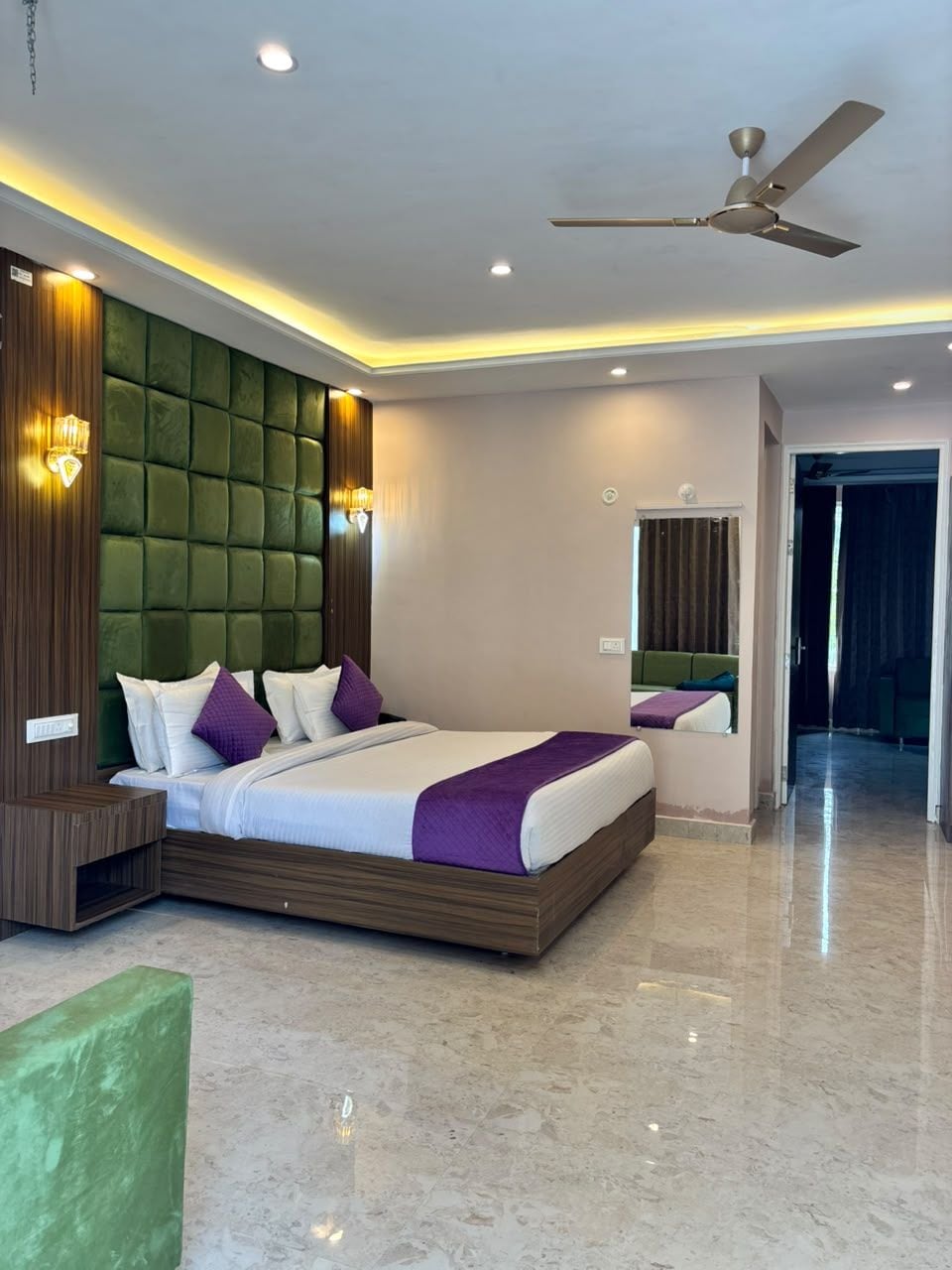 A modern hotel room with a large bed, a ceiling fan, and a mirror.