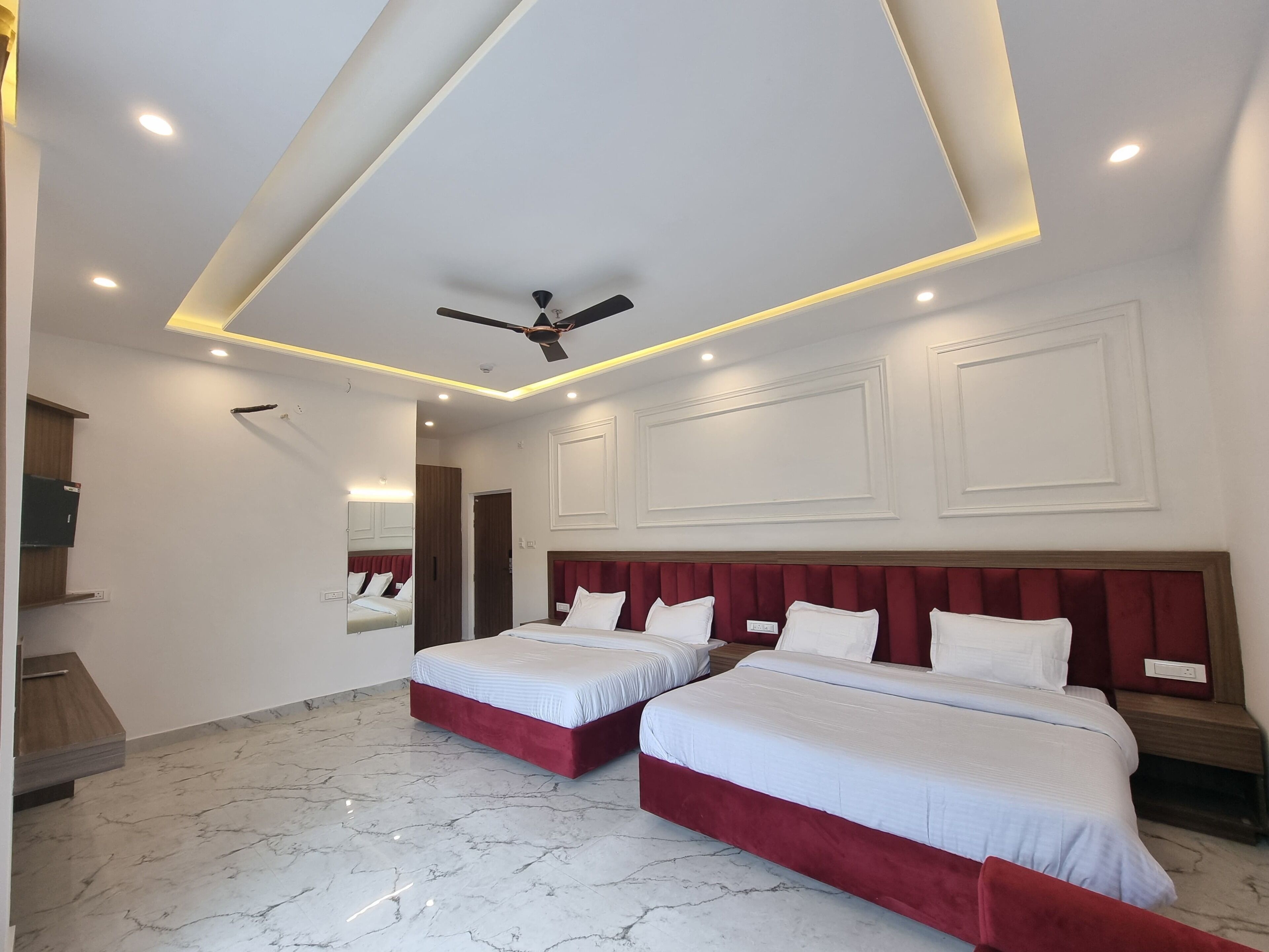 A hotel room with two beds, a ceiling fan, and a marble floor.