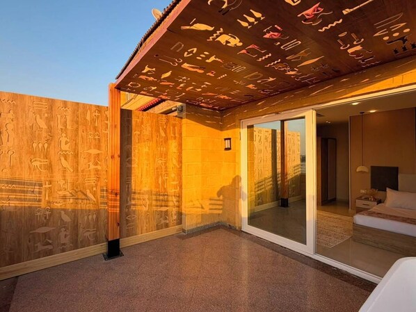 Ein modernes Hotelzimmer mit einer großen Schiebetür zu einem Balkon, der mit ägyptischen Hieroglyphen verziert ist.