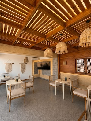 A cozy interior with wooden beams, a fireplace, and wicker furniture. - Gardenia pyramids Palace (Giza)