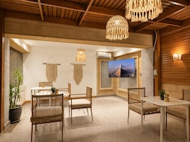 Una habitación con techo de madera, un televisor grande y un comedor con sillas y una mesa.