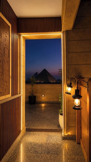 A hallway with a view of pyramids at dusk, wooden paneling, and a potted plant. - Gardenia pyramids Palace (Giza)