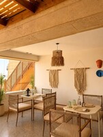 A dining area with a table and chairs, a macrame wall hanging, and a staircase.