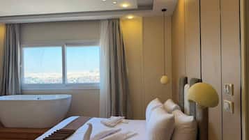 Habitación de hotel moderna con una cama grande, una bañera y vistas a la ciudad.